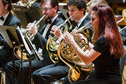 Musicians from the horn choir dress in black perform at an event