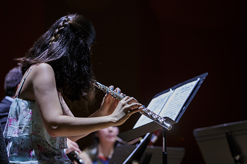 Flute ensemble performing on stage while following the sheet music 