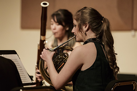 Classical musician dressed in black looks at her sheet music while performing