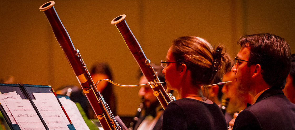 Woodwind players pause as they examine their sheet music during a performance